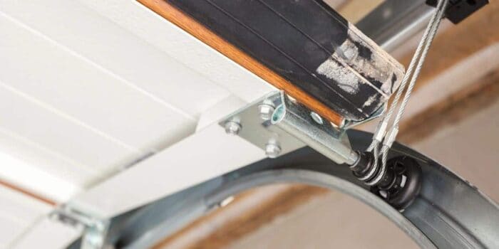 Close-up of a garage door track showcasing a spring mechanism, metal frame, and sturdy cable system.